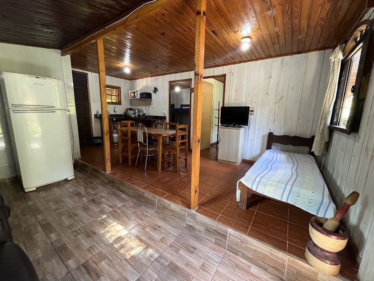 Interior do Chalé Leone, com cozinha equipada, mesa de refeições e sala